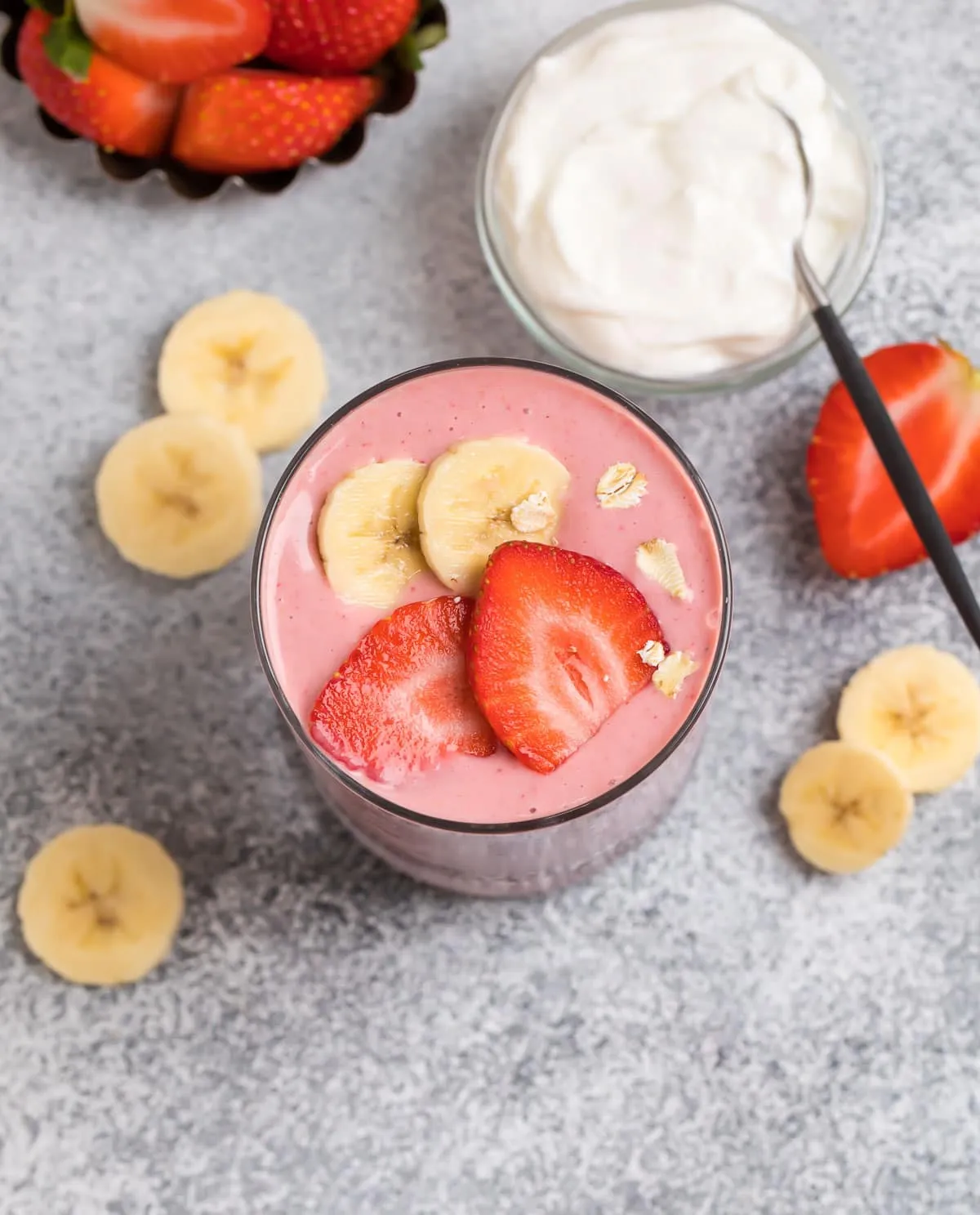 A creamy smoothie served in a glass made with strawberries and bananas