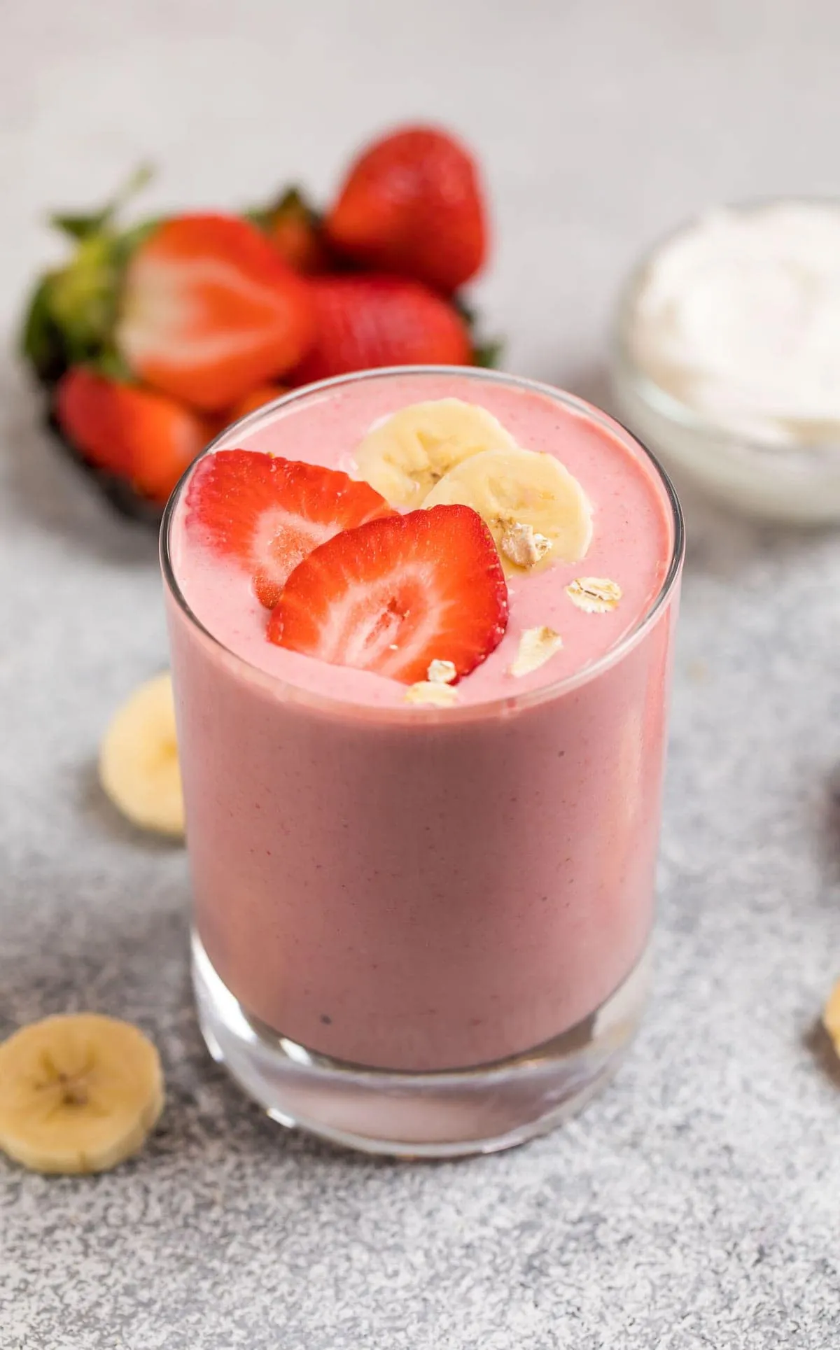 Greek yogurt smoothie in a glass with fresh strawberry and banana slices