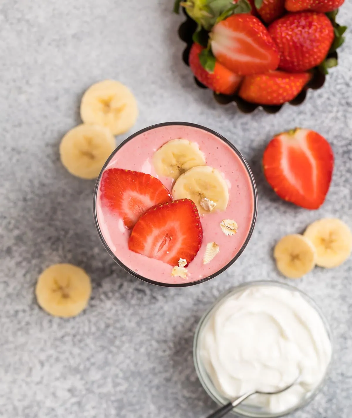 Peanut butter Greek yogurt smoothie served in a glass with fresh strawberries and bananas
