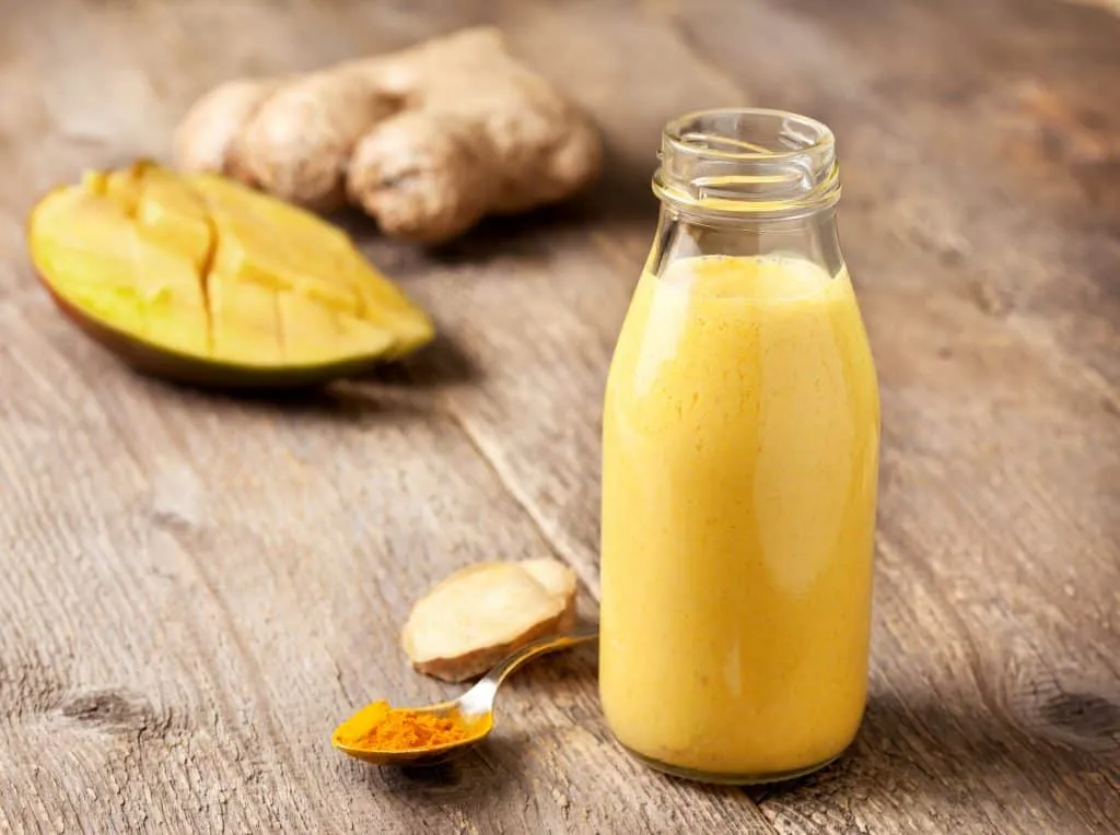 Turmeric smoothie for weight loss in glass jar on wooden background